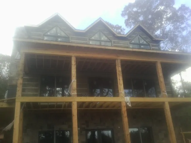 Dormers and porch framing on a large log home under construction — Roof Coating work by our crew in Pascoag