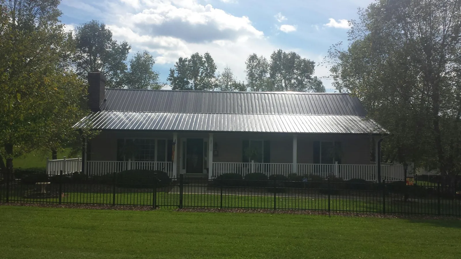 Gray metal roof on a brick ranch with a full width front porch — Gutter Guard Installation work by our crew in Pascoag