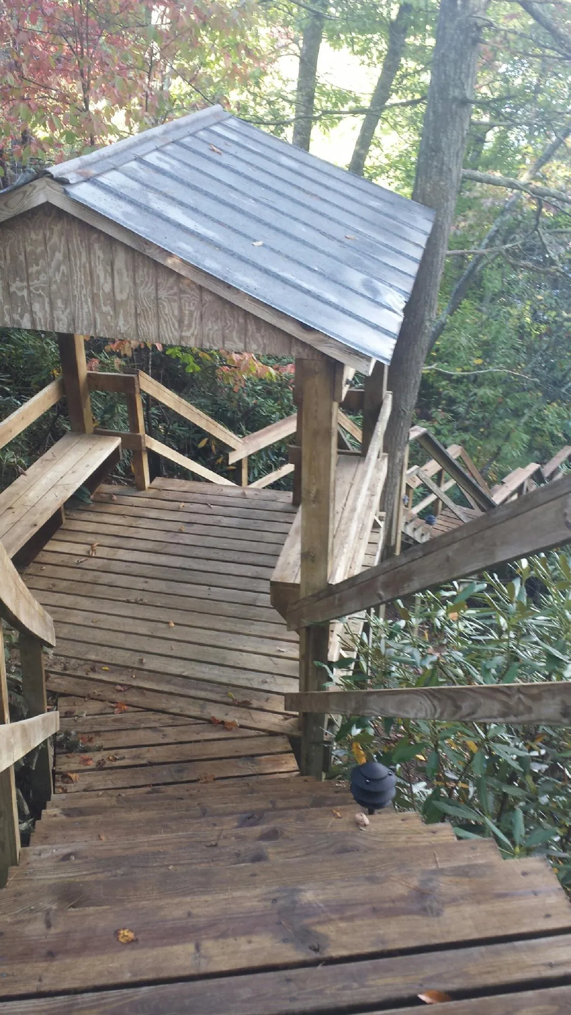 Metal roofed shelter over wooden steps on a wooded walkway — Skylight Repair & Installation work by our crew in Pascoag